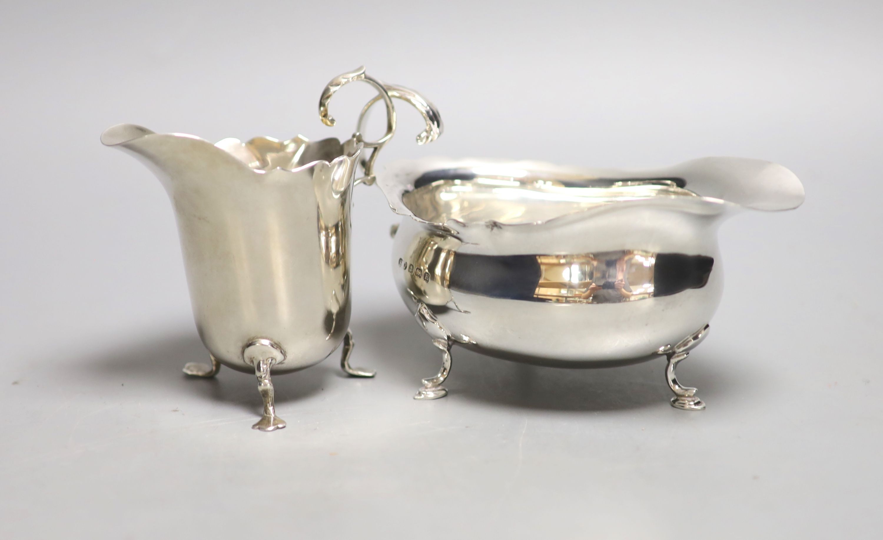 An Edwardian silver cream jug, Birmingham, 1906 and a later silver sauceboat